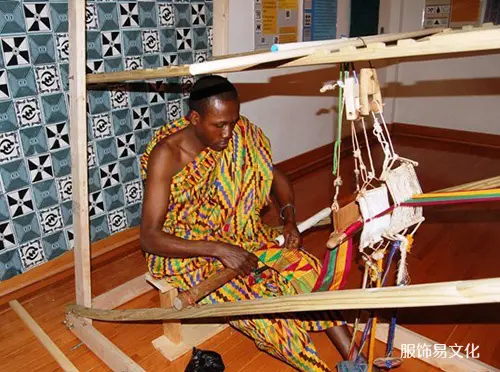 穿着肯特布的男子在木织机上手工编织